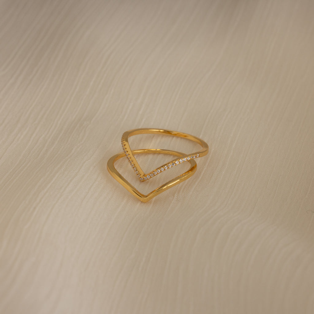 The Curve Stacking Set in 18K Gold—one plain band and one with diamonds—rests on textured cream fabric, perfect for a delicate ring stack.