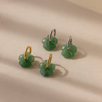 Four Jade Flower Hoops with gold and silver accents are arranged on a beige surface in soft light—dainty earrings that make a meaningful gift.