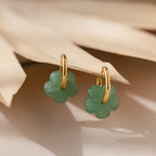 Jade Flower Hoops: Gold hoop earrings with green clover-shaped charms, displayed on a dried palm leaf—these dainty earrings make a meaningful gift.