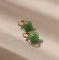 Jade Flower Hoops in 18K Gold rest on a beige surface, softly lit—these dainty earrings make a meaningful gift.