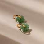 Jade Flower Hoops in 18K Gold rest on a beige surface, softly lit—these dainty earrings make a meaningful gift.