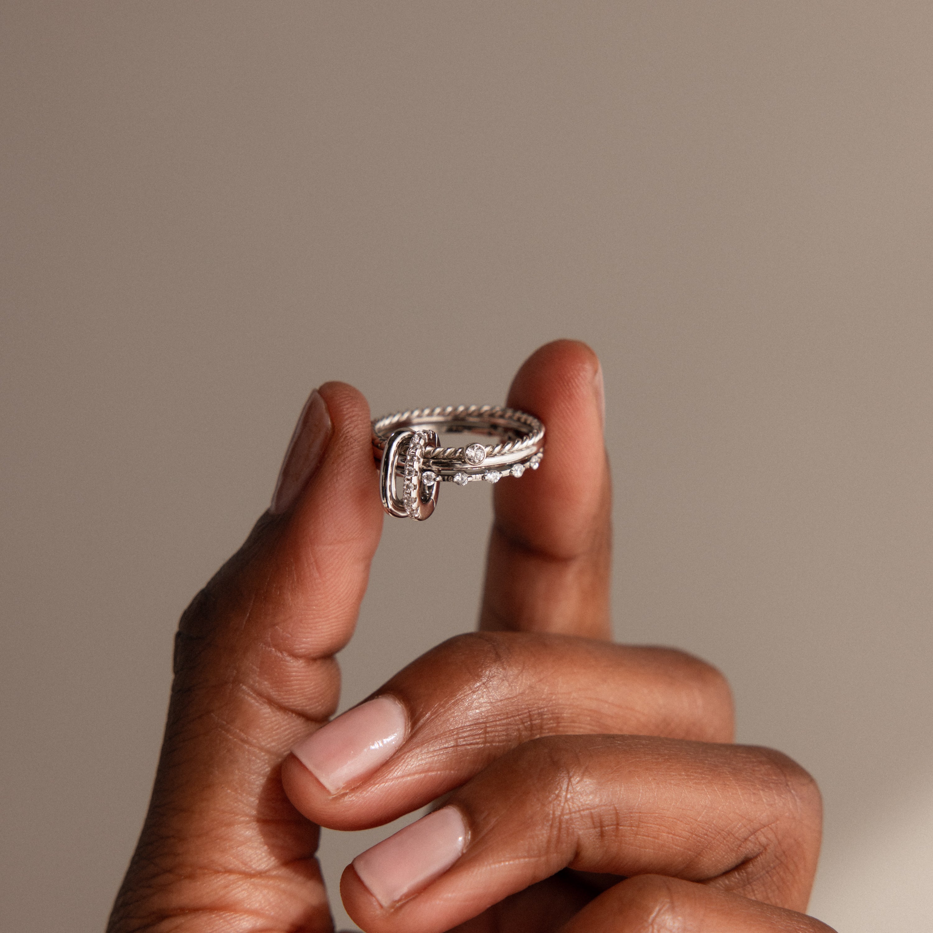 A hand holds the Multipurpose Pave Ring Lock Set, featuring a unique silver design and pavé-detailed clasp, ideal for jewelry customization, set against a neutral background.