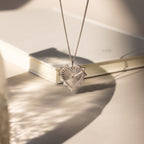 White gold ribbed vintage heart charm dangling from a chain