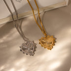 One gold and one white gold ribbed vintage heart  charm on curb chains laying side by side
