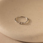 The Delicate Pearl Diamond Ring in Silver features small stones set on a smooth beige surface, perfect for stacking.