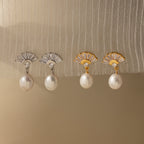 Two pairs of Art Deco Pearl Drop Earrings—one with a silver fan detail, one with gold—add vintage glamour to any outfit and look stunning on light fabric.