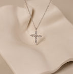 Discover elegance with the Pave Cross Necklace in Silver—a diamond-studded cross pendant on a sleek silver chain, beautifully showcased against a wavy cream-colored backdrop.