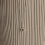 The Padlock Necklace features a silver chain with a small E-engraved pendant, offering a subtle and stylish fashion statement against a textured, light background.