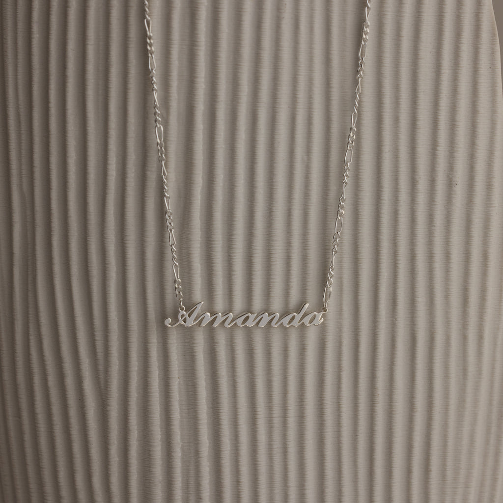 Silver necklace with 'Amanda' pendant on a textured white surface