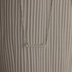 Silver necklace with 'Amanda' pendant on a textured white surface