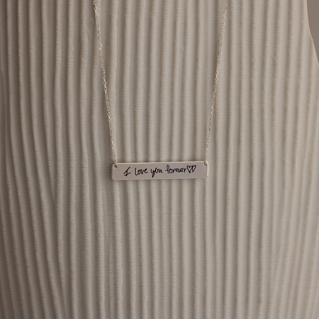 The Handwriting Bar Necklace in Sterling Silver includes a bar pendant engraved with "I love you forever" and two heart symbols, making it a heartfelt personalized jewelry gift.