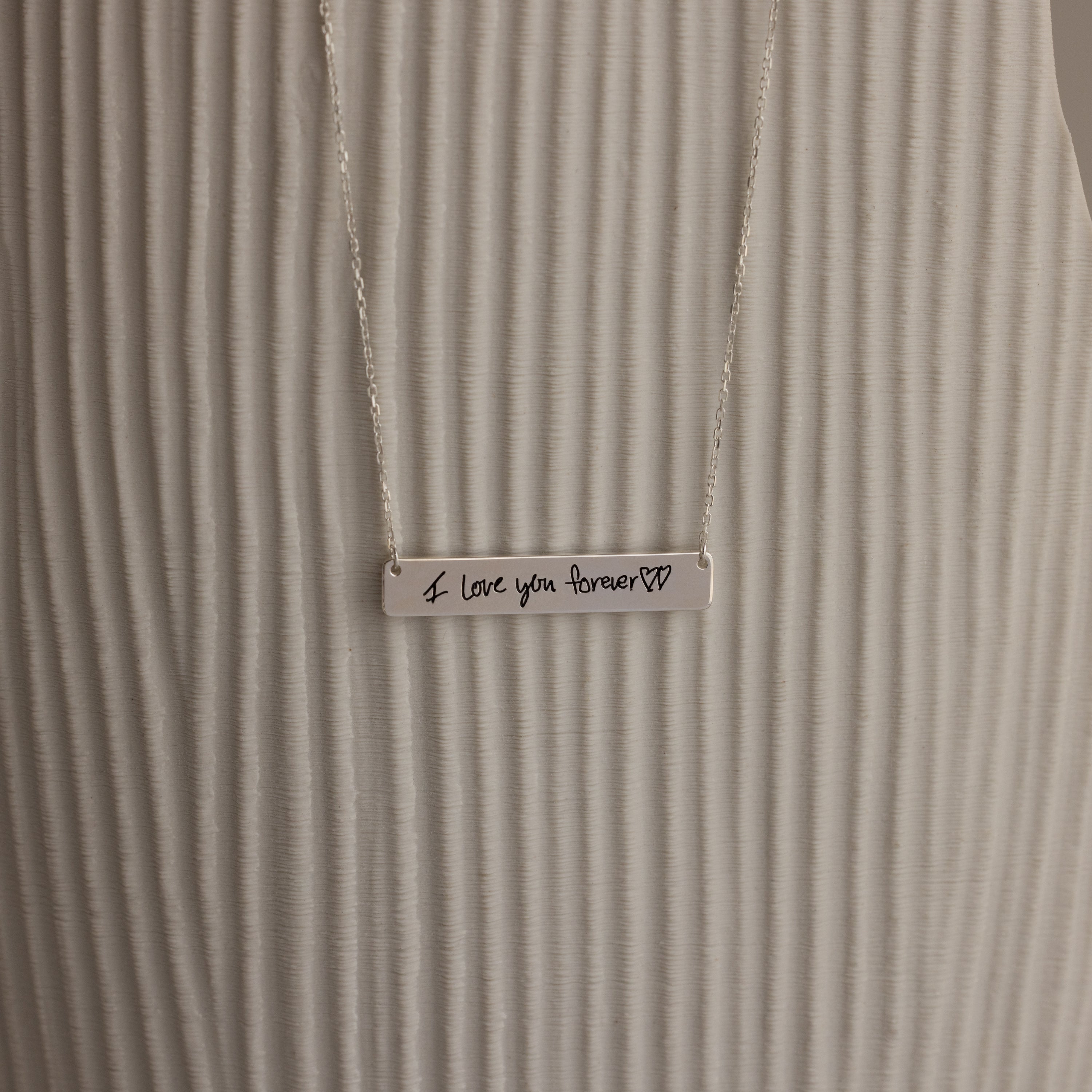 The Handwriting Bar Necklace in Sterling Silver includes a bar pendant engraved with "I love you forever" and two heart symbols, making it a heartfelt personalized jewelry gift.