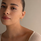 A woman with tied-back hair and a cream top wears Diamond Chain Drop Earrings, gazing softly at the camera against a neutral background.