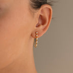 Close-up of a womans ear wearing Diamond Chain Drop Earrings—gold hoops adorned with sparkling stones for an elegant look.