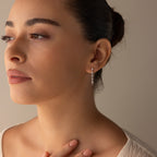 A woman with her hair in a bun, wearing a beige top and Diamond Chain Drop Earrings, gazes thoughtfully to the left.