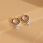 Dangling Pearl Diamond Huggies in Sterling Silver, these elegant earrings are showcased on a peach-colored background.