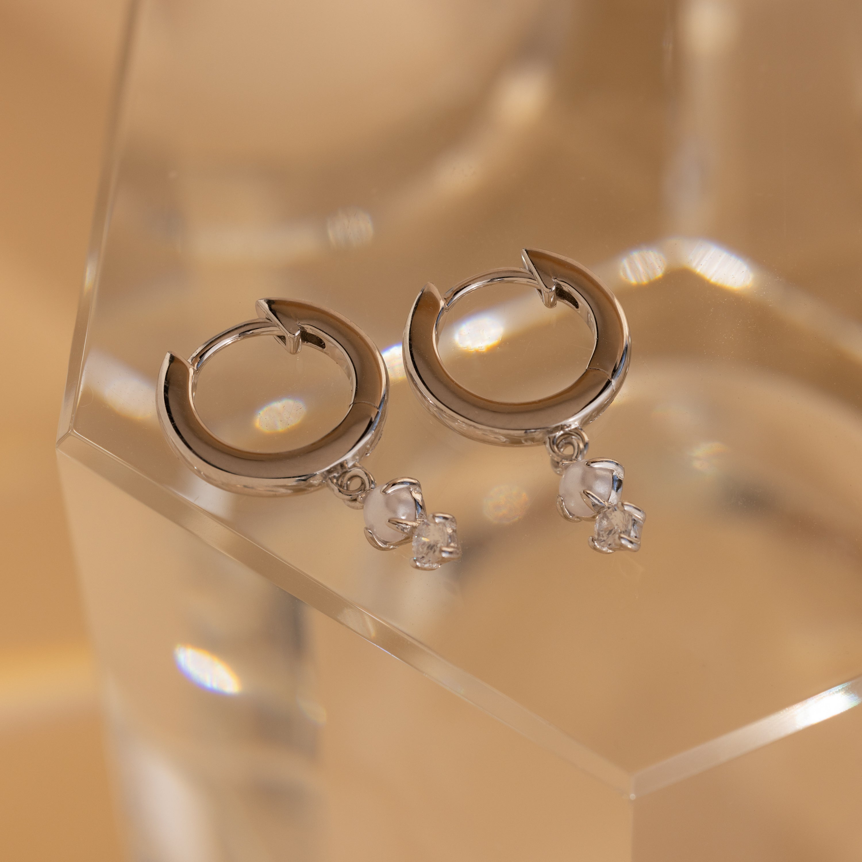 Elevate your style with Dangling Pearl Diamond Huggies in Sterling Silver—these elegant earrings feature sparkling pearl and diamond details for a delicate, timeless look.
