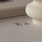 The Toi et Moi Birthstone Ring in Sterling Silver features vibrant blue and pink gemstones—customizable and perfect as a thoughtful Christmas gift, beautifully displayed on a neutral surface.