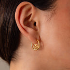 Close-up of an ear wearing Spiral Swirl Hoops in 18K Gold against a light skin tone—ideal boho vacation jewelry for effortless style.