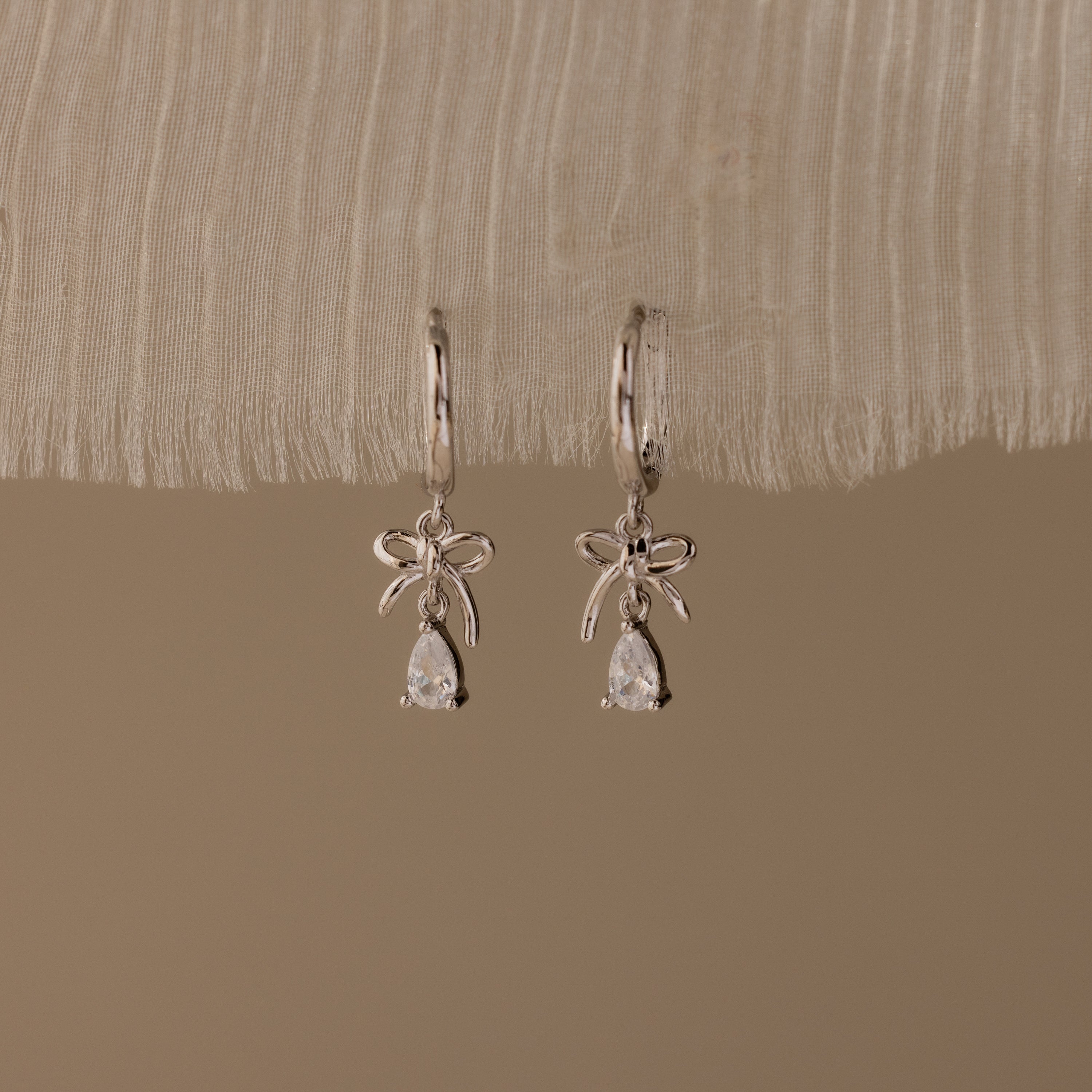 Flatlay of our Teardrop Ribbon Charm Hoops in Silver