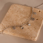 Heart Charm Bracelet in Sterling Silver, featuring delicate heart charms and displayed on a textured beige stone—a thoughtful gift for your girlfriend.