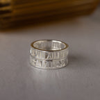 Roman Numerals Ring in Sterling Silver engraved with "FAMILY," shown on a light surface. This personalized piece combines classic style with sentiment, making it a heartfelt milestone gift.