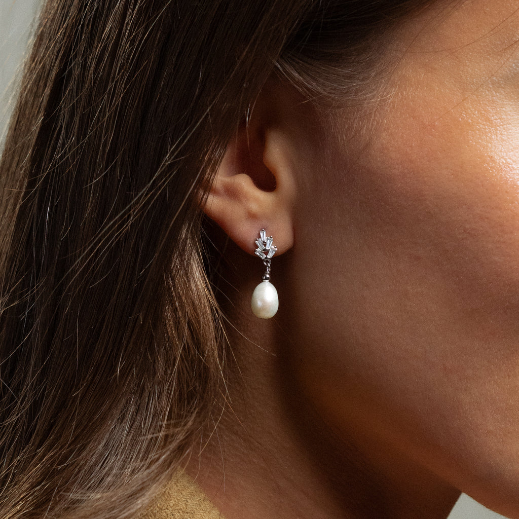 Close-up of a woman wearing Pearl Diamond Drop Earrings in Silver on her left ear.