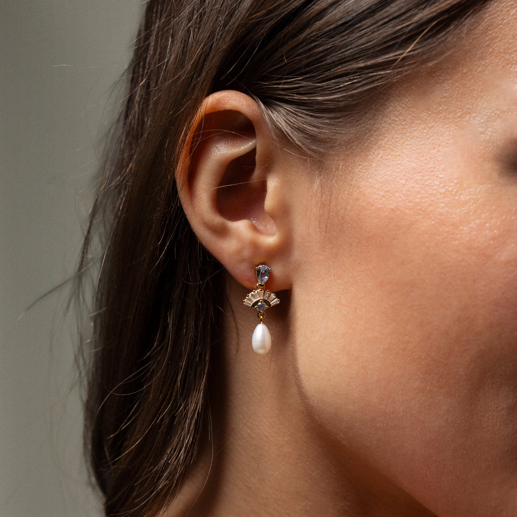 Close-up of a womans ear wearing Aquamarine Pearl Drop Earrings, featuring sparkling gemstones and a dangling pearl for vintage glamour—perfect elegant wedding earrings.