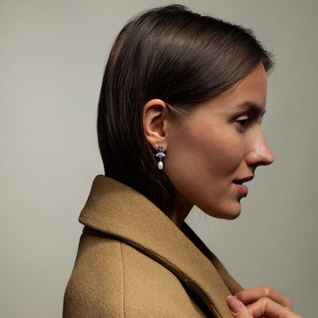 Woman in a brown coat showcases Aquamarine Pearl Drop Earrings in Silver, photographed in profile against a plain background, lending vintage glamour to any outfit.