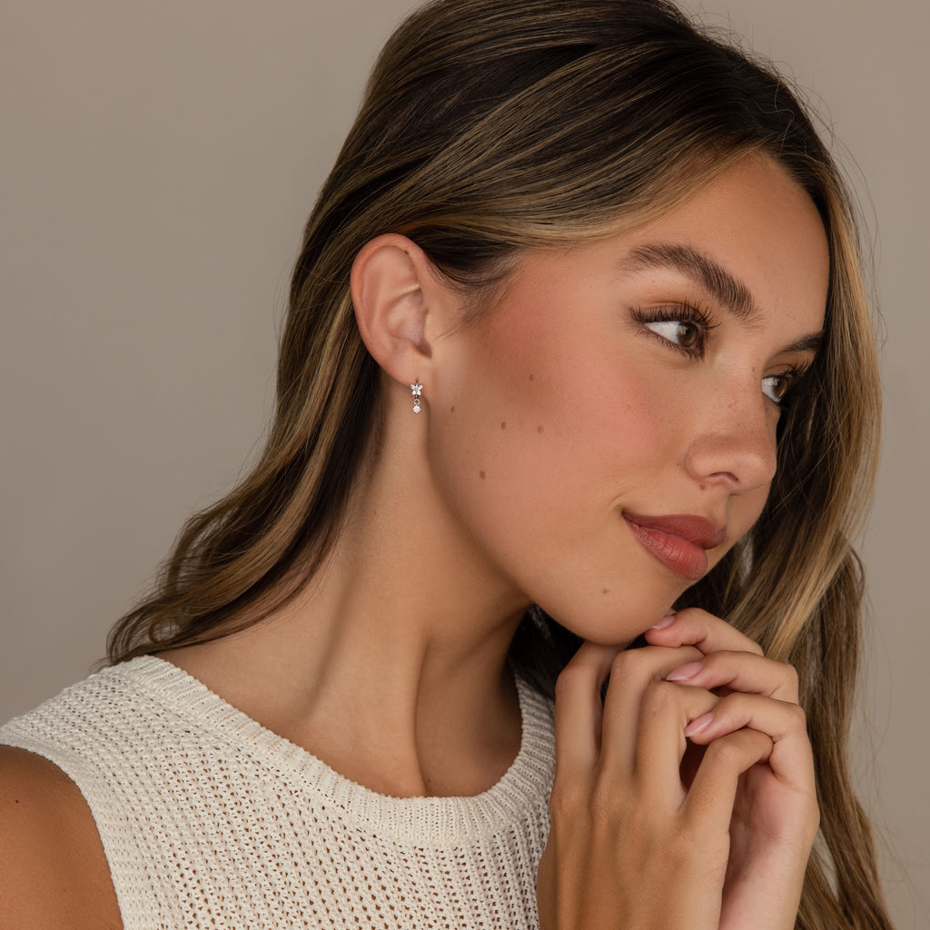 Woman with long brown hair wearing a white knit top and Butterfly Drop Huggies in Sterling Silver with diamond accents, looking to the side.