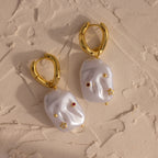 Celestial Baroque Pearl Charm Hoops in 18K Gold showcase irregular white pearls on gold hoops, accented with delicate gold, red, and star charms for a unique celestial-inspired look.