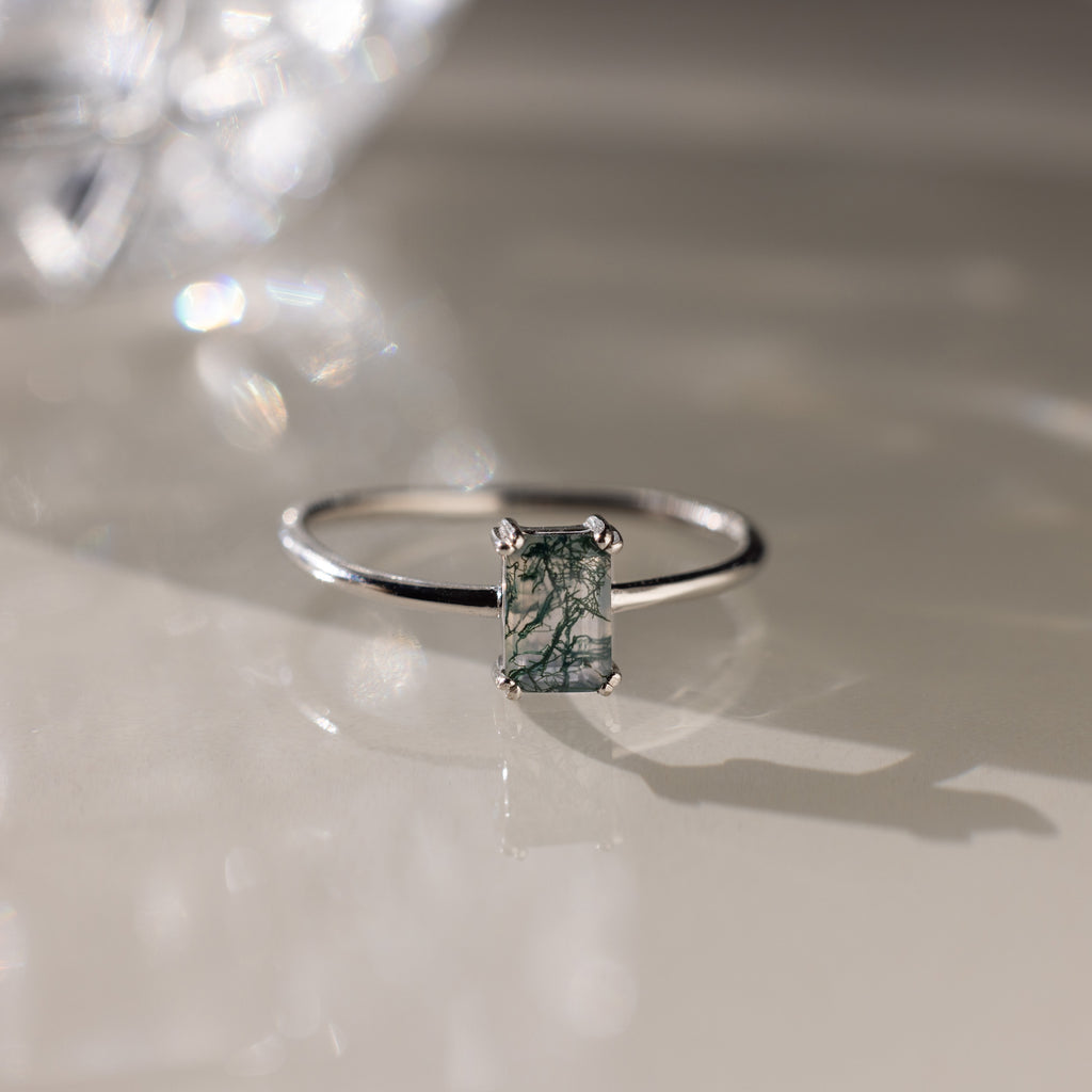 Silver ring with a green agate baguette-cut gemstone on a reflective surface
