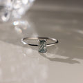 Silver ring with a green agate baguette-cut gemstone on a reflective surface