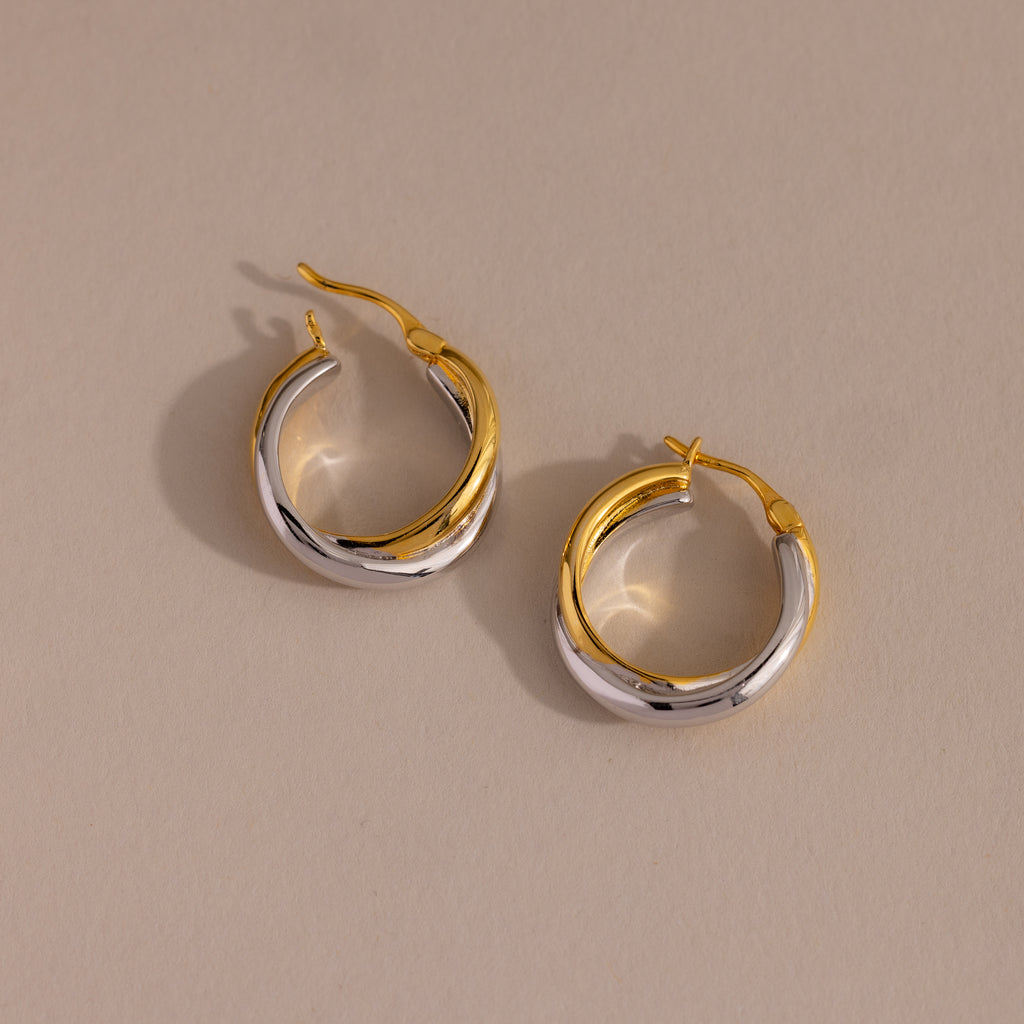Twisted Mixed Metal Hoops—modern gold and silver twisted hoops—are elegantly displayed on a beige background.
