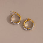 Twisted Mixed Metal Hoops—modern gold and silver twisted hoops—are elegantly displayed on a beige background.