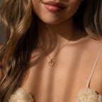 A woman wears a cream floral top and an 18K gold Classic Pearl Heart Charm necklace.