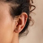 Close-up of a 6mm tiny gold huggie hoop earring worn on the upper ear cartilage, highlighting its snug fit and minimalist shine.