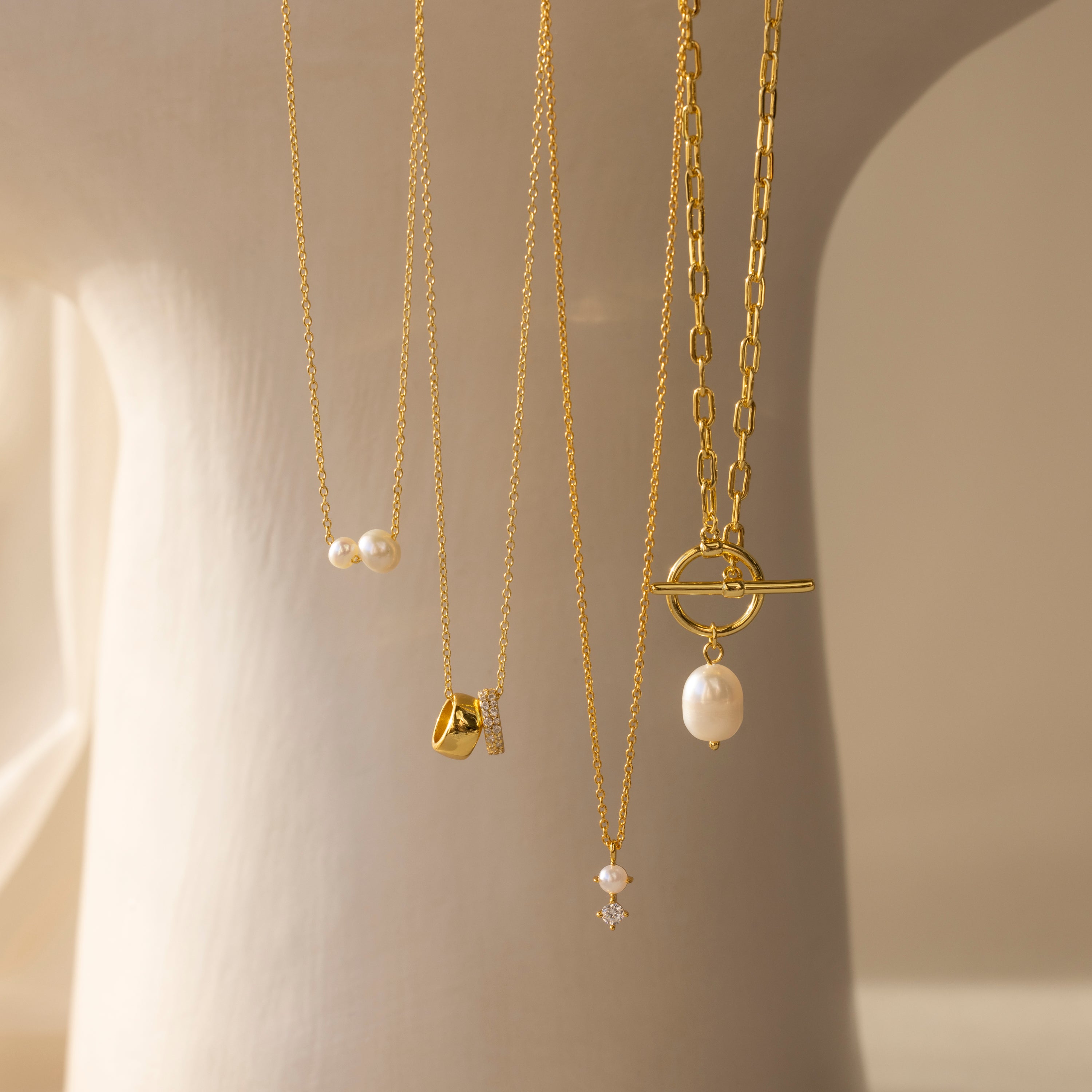 The Dainty Duo Pearl Necklace features gold and pearls, elegantly displayed on a light background—perfect as wedding jewelry or a classic pearl necklace for any occasion.