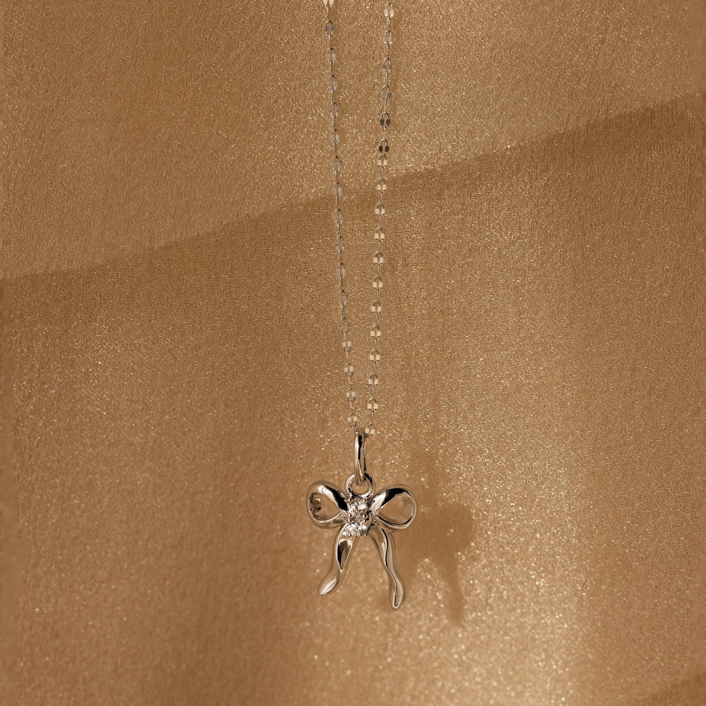 Diamond Bow Charm in Sterling Silver, adorned with CZ diamonds and set against a shimmering gold backdrop—a coquette-inspired accessory that sparkles with elegant charm.