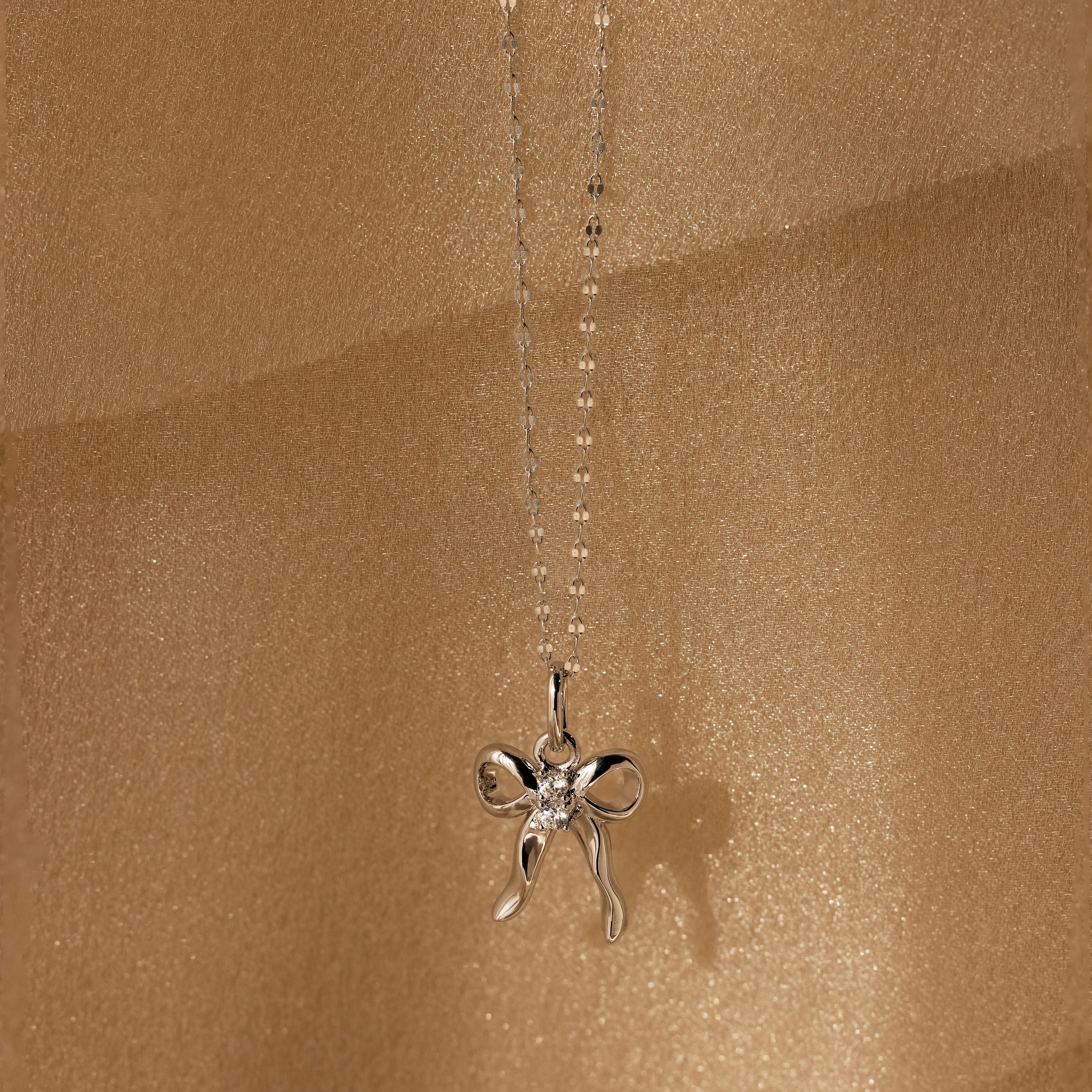 Diamond Bow Charm in Sterling Silver, adorned with CZ diamonds and set against a shimmering gold backdrop—a coquette-inspired accessory that sparkles with elegant charm.