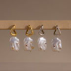 The Celestial Baroque Pearl Charm Hoops in White Gold feature abstract faces, baroque pearls, and gemstone accents—a striking statement earring to elevate any style.