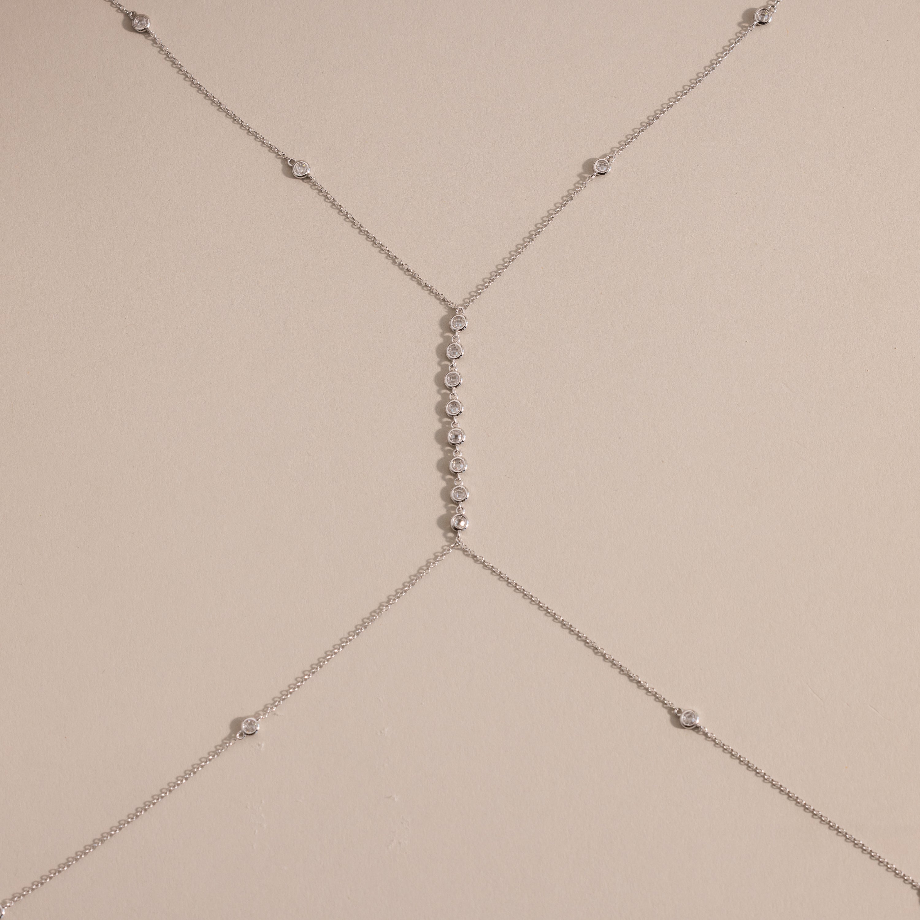 Detailed shot of the silver version of the body chain against a neutral background, featuring the fine chainwork and diamond details.