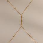 Isolated flat lay of the gold Sprinkle Diamond Body Chain on a neutral background, showing its full design and detailing.