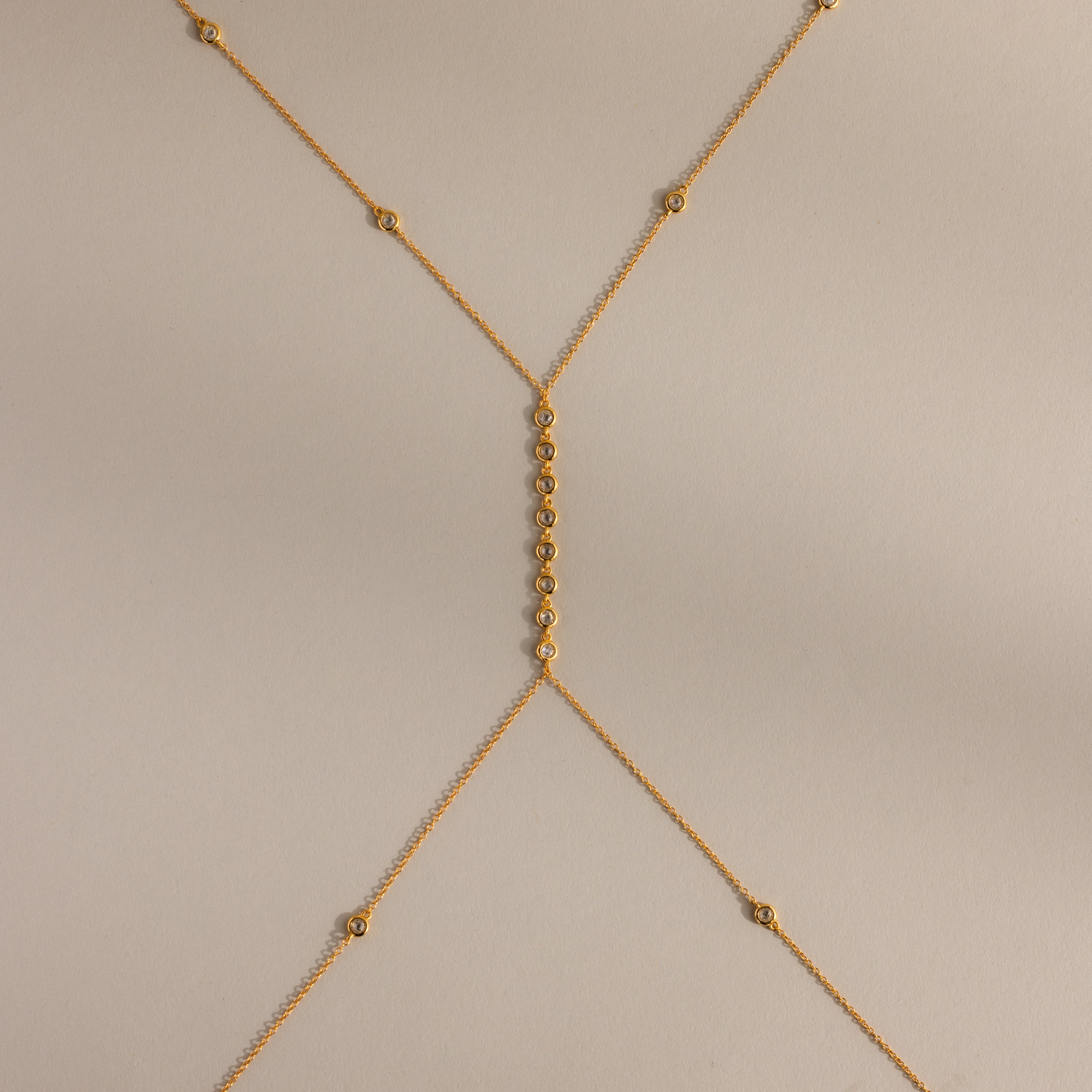 Isolated flat lay of the gold Sprinkle Diamond Body Chain on a neutral background, showing its full design and detailing.