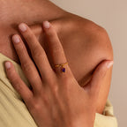 A hand adorned with the Garnet Drop Chain Ring rests on a bare shoulder.