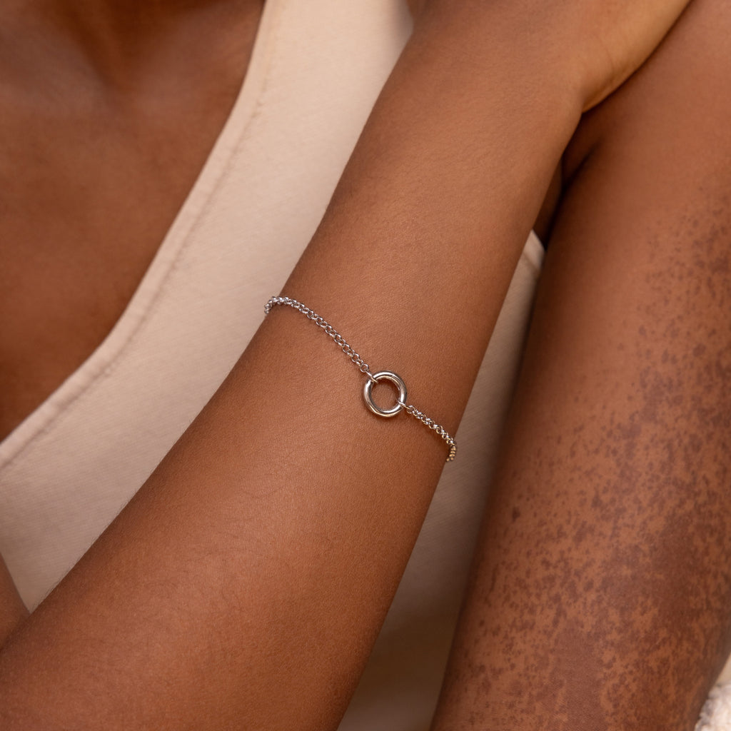 The Rolo Circle Charm Bracelet in White Gold features a sleek chain and detachable hinged circle charm—ideal for personalizing with your favorite charms. Worn with a sleeveless cream top, it adds minimalist elegance to any look.