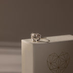 Hand & Footprint Duo Name Ring in Sterling Silver, a perfect keepsake gift for new parents. Presented on a textured box with a geometric heart illustration.