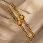 Two elegant women's watches rest on beige fabric: one is a CZ diamond watch with a shimmering bezel, the other is the Pave Blossom Timepiece in Emerald featuring a striking green gem bezel.