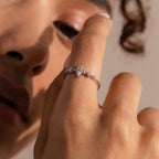A close-up of a hand touching a face, showcasing the Harlow Diamond Ring in Sterling Silver with a marquise diamond under soft lighting.