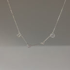 The Dainty Space Charm Necklace in Sterling Silver features letter, heart, and circular charms on a thin chain—perfect for adding a birthstone and personal touch.